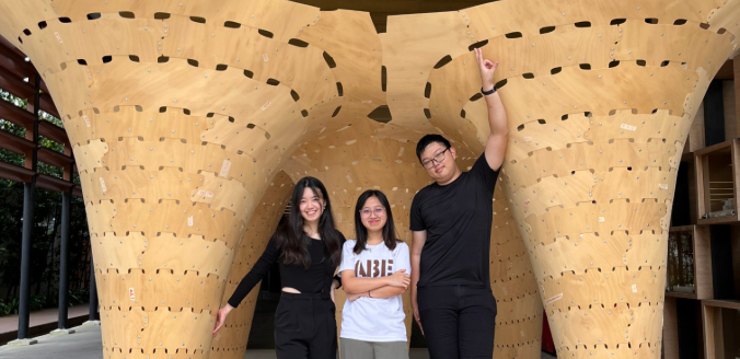 Students posing under an interesting architectural structure