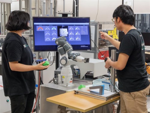 Students adjusting a robotic arm and monitoring the status from a dashboard